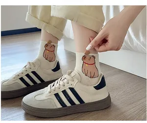 Close-up of cute capybara embroidery on beige cotton socks paired with retro sneakers