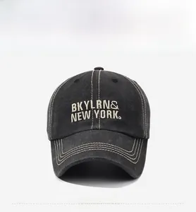 Close-up of white BKYLRN embroidery and yellow contrast stitching on washed denim cap