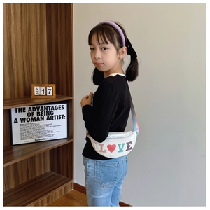 Close-up of child wearing a white LOVE sequin waist bag with a rainbow strap