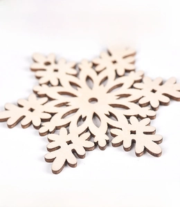 Macro detail of laser-cut wooden snowflake showing the hollow design and natural wood texture