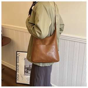 Sac seau en cuir marron avec bandoulière porté en sac fourre-tout sur un mannequin