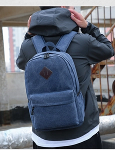 Rear view of a blue canvas backpack with leather pig-snout patch and zipper pocket