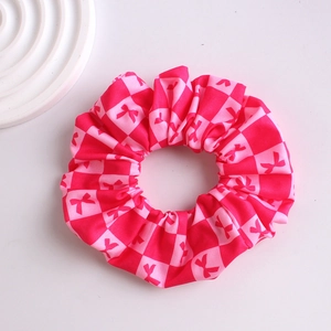 Close-up of pink checkered scrunchie with cute bow patterns on white background