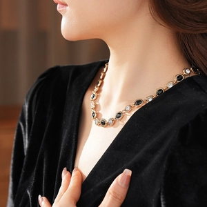 Gros plan d'un collier vintage doré avec gemmes noires et claires sur un mannequin