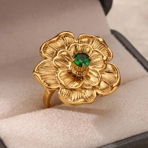 Macro di anello a fiore dorato con gemma verde su espositore in morbido velluto