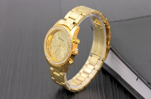 Close-up of golden Geneva watch with diamond-encrusted bezel and metallic link strap