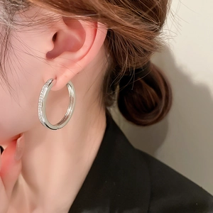 Close-up of silver hoop earring with micro-paved crystals worn on a female ear