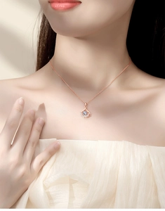 Macro view of rose gold fan-shaped pendant necklace with sparkling stones on model
