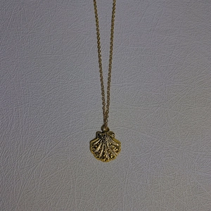 Detailed close-up of a golden conch shell pendant necklace with radial texture and dots