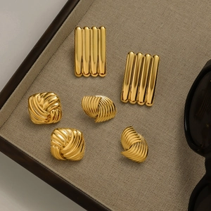 Detailed view of vintage gold plated stainless steel earrings on beige linen display