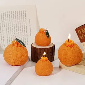 Velas aromáticas realistas con forma de naranja, textura de cítricos y etiqueta de hoja