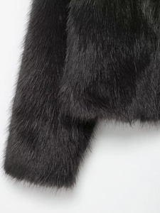 Close-up detail of soft black faux fur texture on cuff and hem of a stand collar coat