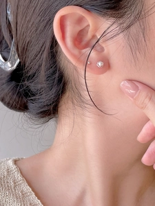 Macro shot of 925 sterling silver pearl flower stud earrings worn on a model's ear