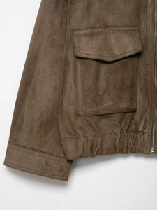 Detail of a brown suede jacket showing functional large utility pockets and zip closure
