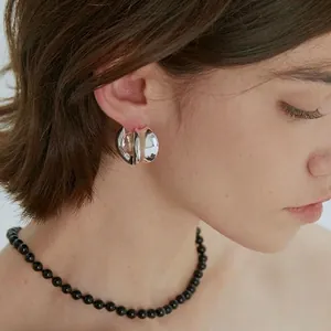 Elegant irregular silver twisted C-hoop earrings with high-polish finish on model