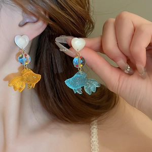 Gros plan de boucles d'oreilles poisson rouge en résine bleue avec perle cœur