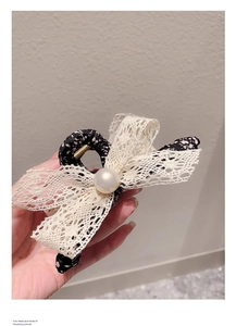 Détail de la pince à cheveux en tissu floral avec nœud en dentelle et perle centrale