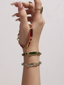 Detail of 18k gold plated bracelets featuring oval red, green, and blue gemstones