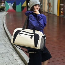 Close-up of a beige canvas travel bag with black straps and adjustable shoulder strap detail