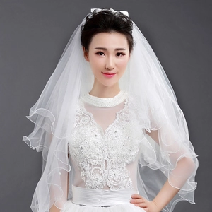 Detail of multi-layer white bridal veil with wavy edges and soft tulle texture on model