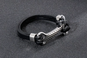 Macro detail of industrial silver wrench clasp on multi-layer black braided leather bracelet