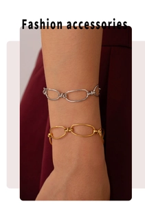 Detail of gold and silver oval link titanium bracelets worn against a burgundy background