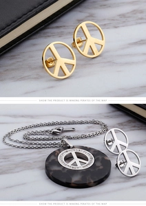 Dettaglio del set orecchini e collana con segno della pace su marmo bianco