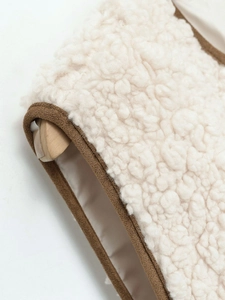 Close-up of soft beige faux shearling vest with contrasting brown piping detail