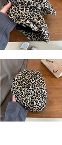 Detailed view of leopard print beret with adjustable silver buckle on wood background