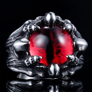 Macro shot of punk gothic dragon claw ring with red evil eye stone on black background