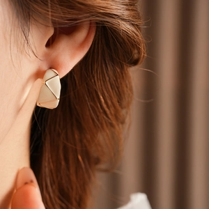 Detailed view of vintage enamel C-shape earring in cream white and gold on model