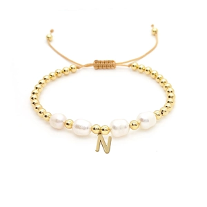 Detailed macro view of an 18K gold bead bracelet with natural pearls and a letter N pendant