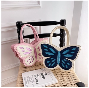 Detailed view of butterfly-shaped handbags with sequined wings on a wicker chair