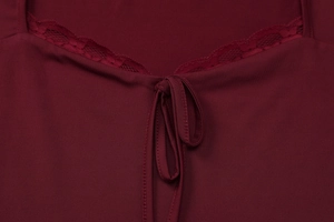 Détail d'un haut en maille bordeaux avec bordure en dentelle et un nœud délicat au col