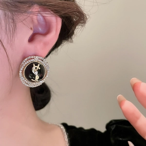 Close-up of luxury round stud earrings with gold logo and double-layered crystal halo
