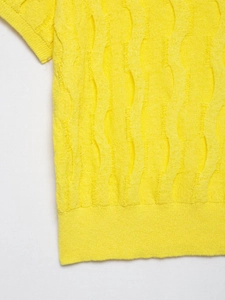Vista detallada del tejido de punto amarillo con un diseño calado ondulado único