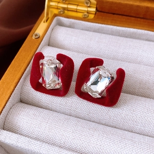 Close-up of red velvet square stud earrings with central crystal on jewelry box