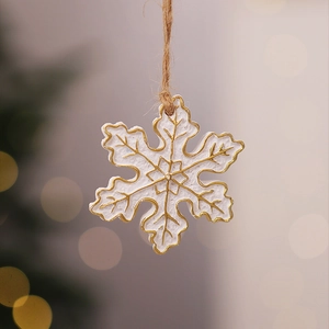 Macro detail of a white and gold snowflake resin ornament with a natural jute rope hanger