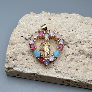 Golden heart pendant with multi-colored crystals and religious embossed icon on stone