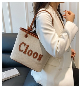 Detail of cream canvas tote bag with brown leather handles and Cloos logo embroidery