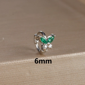 Macro shot of 6mm silver butterfly cartilage hoop with green and white gemstones