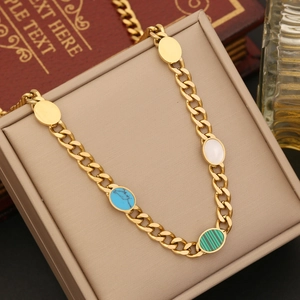Close-up of gold Cuban chain necklace with colorful oval stones on a jewelry box