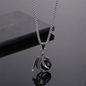 Vue détaillée du pendentif griffe de dragon avec perle noire et chaîne acier