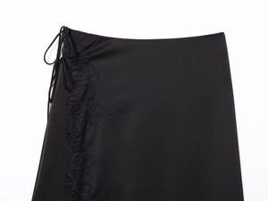 Detailed close-up of smooth black satin fabric with delicate eyelash lace trim details