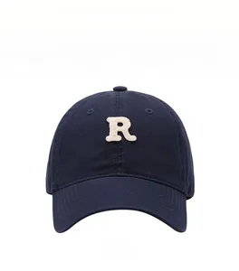 Detail of navy blue baseball cap featuring a white towel-embroidered R letter on front