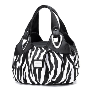 Detailed view of zebra print handbag with black handles and silver fashion metal plaque
