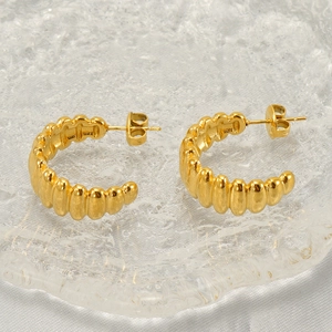 Détail de boucles d'oreilles dorées en C en acier inoxydable à texture ondulée