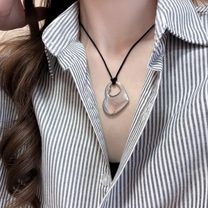 Close-up of hollow heart pendant necklace on model with black cord and silver finish
