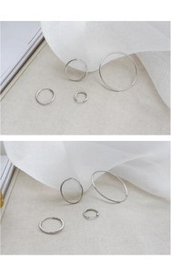 Detail shot of various sized S925 sterling silver minimalist hoop earrings on white fabric
