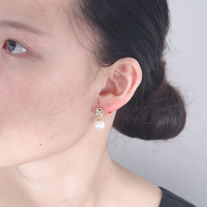 Close-up of golden clover diamond earrings with elegant white round pearls on model